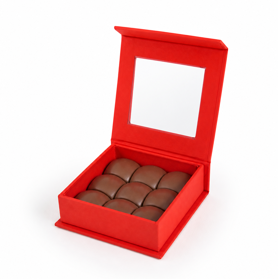     Open box of pistachio praline chocolate domes by La Belg